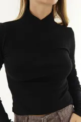 Polera blanca de algodón con cuello alto cruzado y mangas largas.