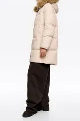Campera tipo plumífero de largo medio y corte recto en tejido técnico, con cierre frontal, capucha con borde de pelo sintético desmontable y puños elásticos interiores. Presenta bolsillos laterales de vivo y etiqueta con logo en el pecho.