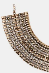 Maxi collar tipo choker de diseño rígido y estructurado, compuesto por múltiples filas de piezas metálicas doradas intercaladas con pequeñas incrustaciones de cristales brillantes.