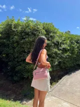 Bandolera de diseño moderno y funcional, confeccionada en nylon color marrón claro. Cuenta con múltiples compartimentos con cierre metálico, herrajes plateados y una correa ancha ajustable con detalle de marca.