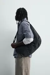 Bolso de hombro tipo hobo fabricado en tejido técnico de nylon. Cuenta con un compartimento principal con cierre de cremallera, un bolsillo interior con cierre y un asa ajustable con detalle de mosquetón.