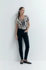 Pantalón de mezclilla ajustado (slim fit) color crudo, de tiro medio/alto, con cinco bolsillos y cierre de cremallera y botón.