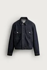Campera de denim azul oscuro de corte cropped, con cuello camisero, bolsillos delanteros con solapa y cierre frontal oculto con botones metálicos.