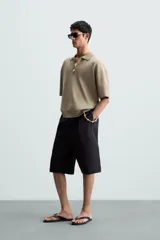 Polo de punto color verde oliva, de manga corta y corte relajado. Presenta cuello solapa con cierre frontal de cremallera.