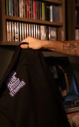 Remera de algodón premium con calce oversize, cuello redondo y mangas cortas. Presenta un estampado frontal gráfico con temática de Daft Punk en tonos verdes y violetas sobre fondo negro.