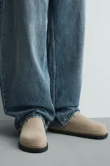 Zueco de piel con acabado serraje color beige, con plantilla anatómica, horma redonda y suela de volumen negra.