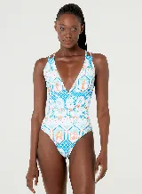 Traje de baño enterizo blanco con estampado de figuras geométricas en tonos celeste, naranja y verde. Tiene escote en V, breteles finos dobles y espalda cavada.