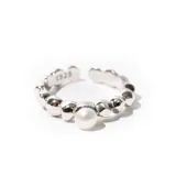 Anillo plateado ajustable con una perla central.