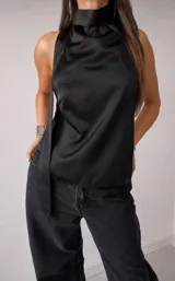 Top de satén negro con cuello halter alto y lazo lateral decorativo. Diseño sin mangas con caída fluida.