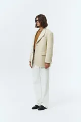 Blazer de lana con mezcla de alpaca en color beige, con cuello sastre, cierre frontal de dos botones y bolsillos laterales con solapa. Presenta una textura suave y vellosa.