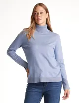 Polera de tejido fino color celeste, con cuello alto, manga larga y detalle de tajo en los puños.
