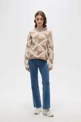 Sweater de punto con diseño geométrico de rombos en tonos beige y marrón, cuello alto tipo polera y mangas largas.
