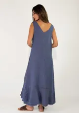 Vestido largo sin mangas de lino azul, con escote en V, bolsillos laterales y detalles de costuras marrones a la vista con terminaciones deshilachadas en el bajo.