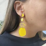 Aros colgantes amarillos con formas geométricas irregulares.
