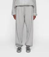 Pantalón de jogging gris de corte recto y estilo oversize, confeccionado en felpa de algodón. Presenta cintura elástica con cordón, bolsillos laterales y traseros, etiqueta con logo y puños elásticos en los tobillos.
