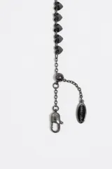 Pulsera de cadena fina dorada de acero inoxidable con una hilera de cristales de vidrio en forma de corazón de múltiples colores. Incluye cierre de mosquetón ajustable y dije de la marca.