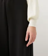 Cárdigan color crema de punto con cuello camisero, manga larga abullonada, cierre frontal abotonado y bolsillo de parche en el pecho.