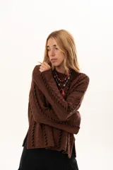 Buzo de tejido de punto color chocolate con diseño de trenzas verticales y detalles de costuras en contraste color negro. Presenta cuello redondo, mangas largas con terminación acampanada y aberturas laterales en el ruedo.