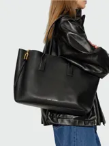 Cartera tipo tote bag Marc Jacobs The Puffy J Marc Work Tote, color negro con herrajes dorados y logotipo de la marca impreso en el frente.