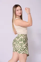Short pollera con estampado tribal en tonos beige y verde, con cierre de lazo lateral y detalle de borlas.
