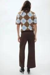 Pantalón de punto color marrón, de tiro alto con cintura elástica y diseño de piernas amplias con pliegues frontales cosidos.