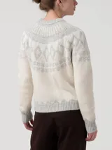 Sweater de punto con diseño jacquard circular en el yugo, mangas y ruedo. Presenta cuello redondo, mangas largas y puños acanalados en un tono beige claro con detalles en gris.