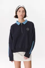 Buzo estilo rugby de corte oversized, confeccionado en algodón color azul marino. Presenta cuello tipo camisa en denim celeste, cierre frontal parcial con cremallera, logo bordado en el pecho y bandas laterales en las mangas en contraste de color.