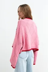 Sweater de punto color rosado con diseño jacquard de peces azules en el pecho, cuello redondo, puños y ruedo en tono rojo contrastante. Presenta textura en rombos y mangas largas holgadas.