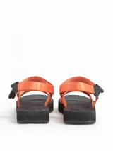 Sandalias planas con tiras de poliéster color naranja y suela negra.