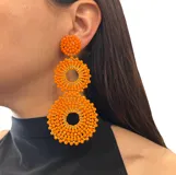 Aros colgantes color naranja, con forma de círculos tramados con cristales.