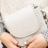 Mini cartera bandolera de cuero, de formato compacto y diseño atemporal con solapa frontal y costuras artesanales decorativas en el borde. Cuenta con el logotipo de la marca grabado en la parte delantera y correa larga regulable.