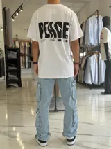 Remera oversize blanca de manga corta, con gran estampado negro en la espalda con la palabra 'Peace' y símbolos gráficos.