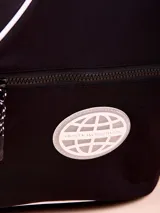 Mochila tipo bandolera (sling bag) de color negro con detalles de ribetes blancos. Presenta un diseño ergonómico de una sola correa, bolsillo frontal con cierre y logo circular de la marca Rusty. Incluye hebilla de ajuste lateral.