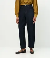 Pantalón de jean corte carrot, color azul oscuro, con cintura alta, cierre frontal con cremallera y botón, y bolsillos laterales.