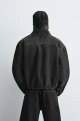 Cazadora de denim de algodón en color negro con interior acolchado. Presenta un corte boxy fit, cuello solapa, cierre frontal con botones, bolsillo plastrón en el pecho y bajo ajustable con cordón.