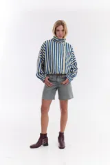 Chaqueta bomber de algodón con estampado a cuadros en tonos azules, amarillos y marrones, cuello alto y cierre frontal descentrado con botones. Cuenta con mangas abullonadas y puños elásticos.