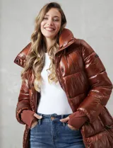 Campera puffer larga de abrigo marca BCBG Maxazria, color beige. Cuenta con capucha desmontable, cuello alto envolvente, cierre frontal bidireccional con solapa de botones a presión, bolsillos laterales, puños internos elastizados y tajos laterales con cierre en el bajo.