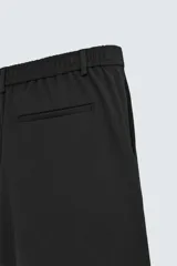 Bermuda de hombre color verde claro, de corte regular y tiro medio, con pinzas frontales, bolsillos laterales y bolsillos traseros de vivo. Cierre frontal con botón y cremallera.