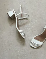 Sandalias de tacón bajo color blanco, con tiras finas y cierre con hebilla.