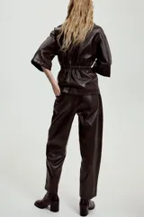 Pantalón de tiro alto confeccionado en material efecto piel, con cintura elástica ajustable mediante cordones, bolsillos delanteros y bolsillos de plastrón en la parte trasera.