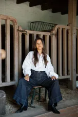 Camisa de lino de corte relajado y silueta holgada, con cuello clásico y cierre frontal de botones forrados en lino a rayas. Presenta mangas largas con puños amplios.