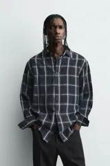 Camisa de corte relajado confeccionada en tejido fluido de cupro y viscosa, con estampado de cuadros, cuello solapa, manga larga con puño abotonado y cierre frontal de botones.