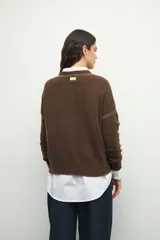 Sweater de tejido de punto color marrón, con cuello redondo y detalles de calados decorativos en el cuello y las mangas. Presenta un diseño de corte recto y manga larga.
