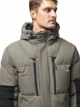 Campera puffer con capucha, de diseño bicolor en tonos gris topo y negro. Presenta cierre frontal con solapa de botones, bolsillos laterales y ajuste en los puños.
