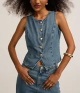 Chaleco de jean azul con cuello redondo y cierre frontal de botones metalizados con relieve. Presenta recortes verticales que definen la silueta y un bajo acabado en pico. Confeccionado en tejido de algodón denim.