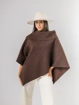 Poncho de tejido texturizado en color marrón chocolate, con cuello amplio y diseño asimétrico.