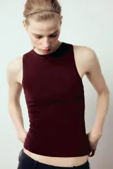 Top de punto color crema, sin mangas, con cuello redondo y corte ajustado.