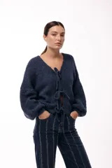 Saco tejido de punto color azul, con escote en V y cierre frontal mediante lazos. Presenta mangas largas amplias con puños ajustados y un calce relajado.