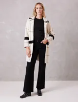 Chaqueta de tejido suave con estampado a cuadros en tonos beige y blanco, cuello con solapa y cierre de botón frontal. Incluye bolsillos delanteros.