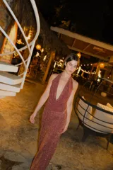 Falda larga tejida color marrón con brillo metálico, corte al cuerpo, abertura alta en la pierna y recortes laterales con cordones ajustables.